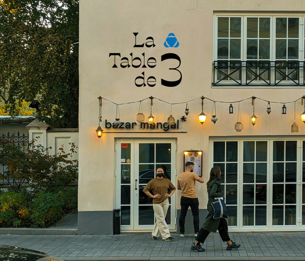 Une serveuse attend devant la porte du restaurant la table de trois à Bordeaux.