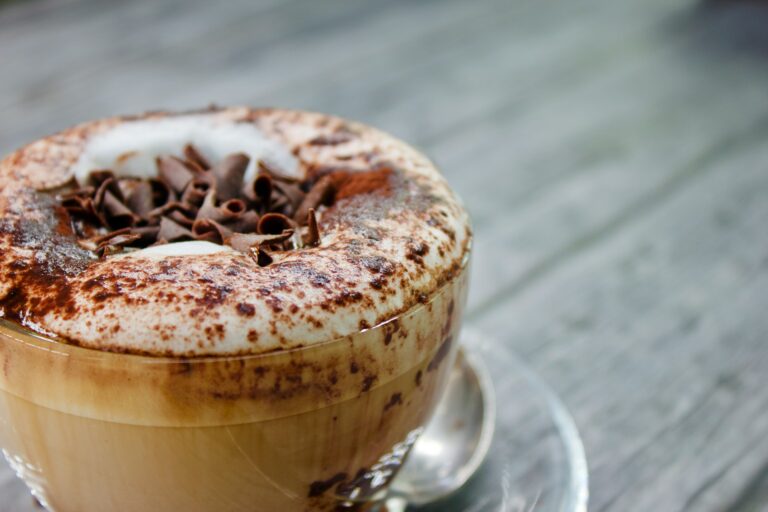 Gros plan sur une tasse de capuccino gourmand avec de la mousse et des copeaux de chocolat du restaurant la table de trois à Bordeaux.