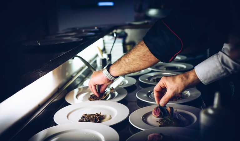 Gros plan sur deux avant bras de cuisiniers qui dressent délicatemeny des plats du restaurant la table de 3 à Bordeaux.