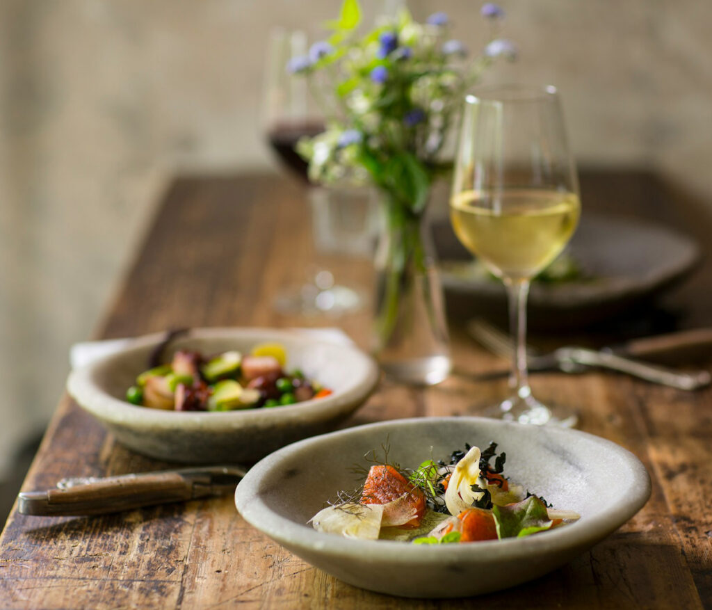 Assiette de saumon fumé et de crudités sur une table en bois et un verre de vin blanc au restaurant la table de 3 à Bordeaux.