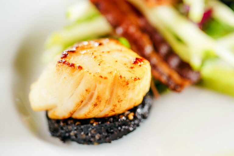 Noix de Saint-Jacques sur un lit de riz noir du restaurant la table de trois à Bordeaux.