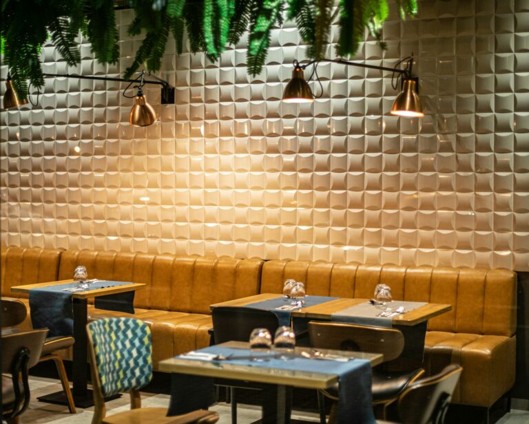 Salle de restaurant décorée avec des banquettes jaunes et des plantes au plafond à la table de trois à Bordeaux.