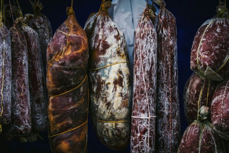 Plusieurs saucissons et charcuteries en grand nombre suspendues du restaurant la table de trois à Bordeaux.