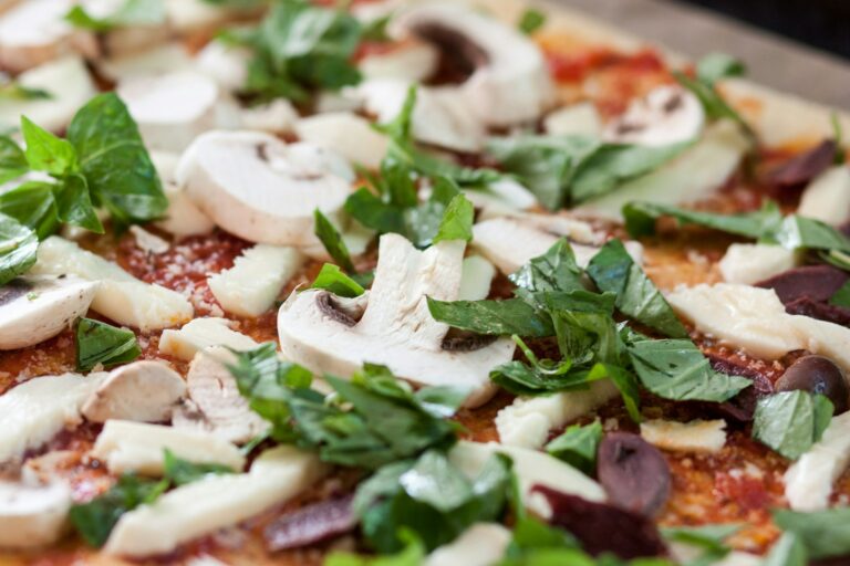Zoom d'une pizza sur des champignons de paris et du basilic frais du restaurant la table de 3 à Bordeaux.